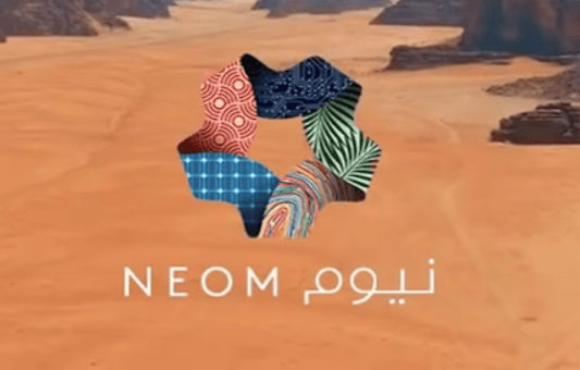 A stylized multicolored star-shaped logo with geometric patterns sits above the word NEOM in English and Arabic, set against a desert landscape known for hosting extreme sports amid striking rocky formations.